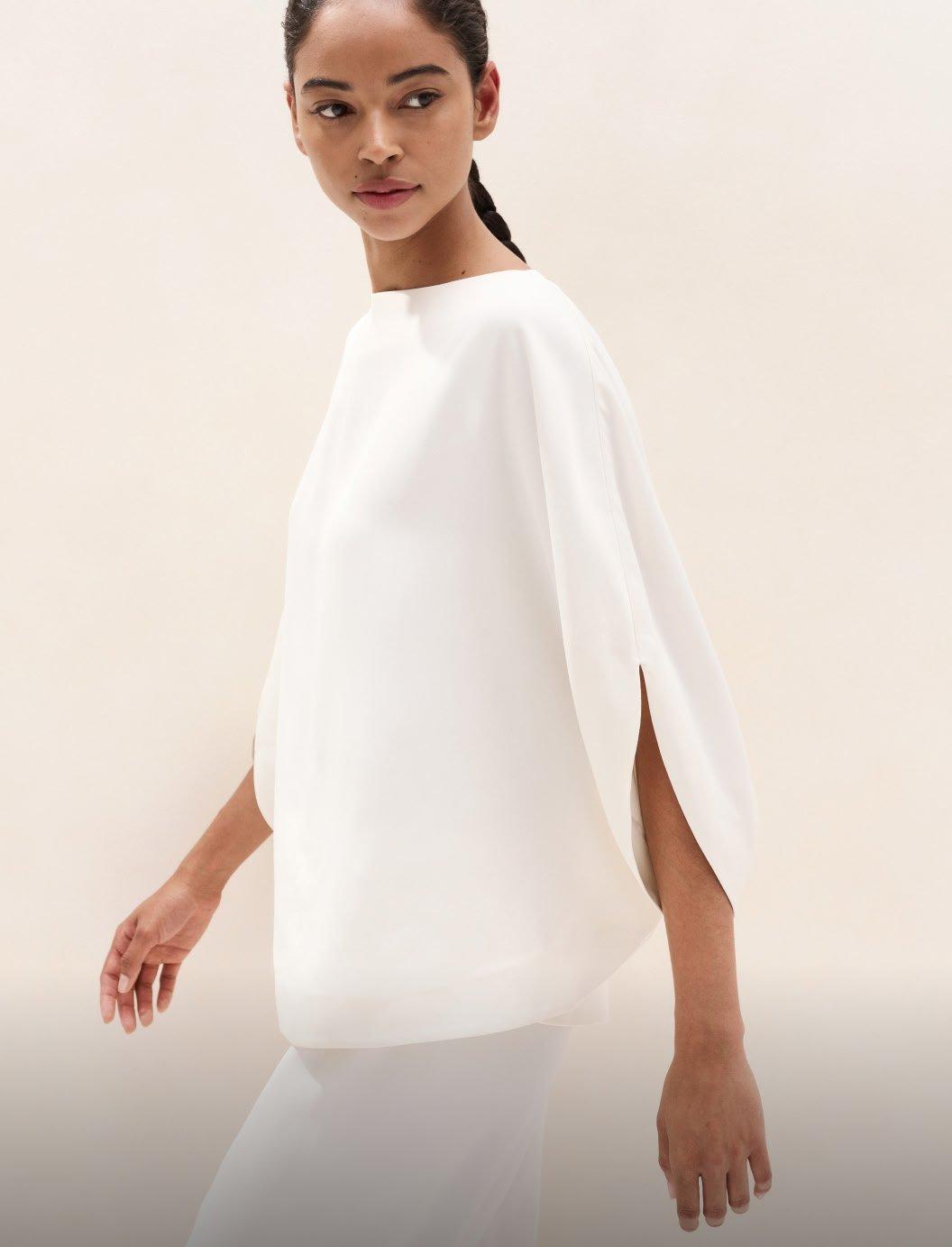 a woman in white dress walking down a runway