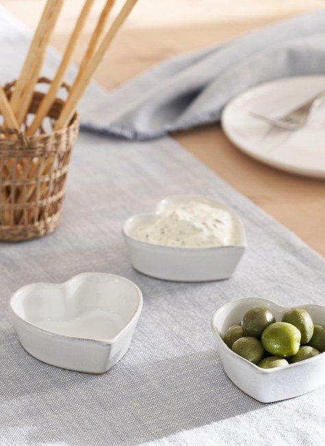 a table with three bowls of olives and a bowl of bread