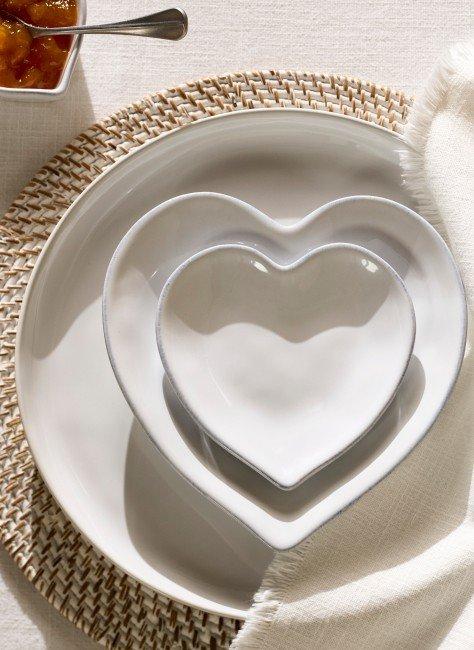 a white plate with a heart shaped bowl on top of it