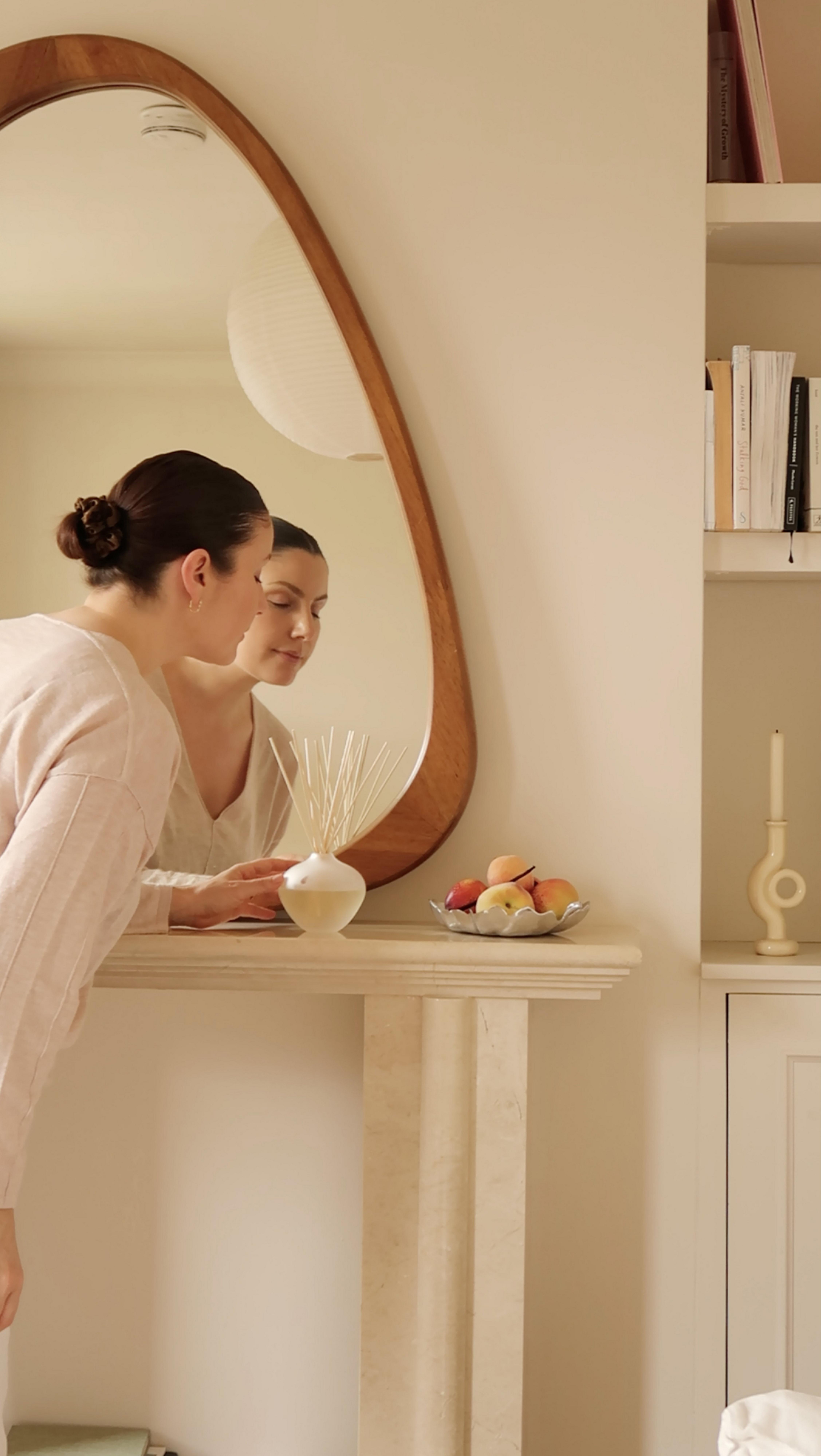 a woman in white robe looking in mirror at her reflection