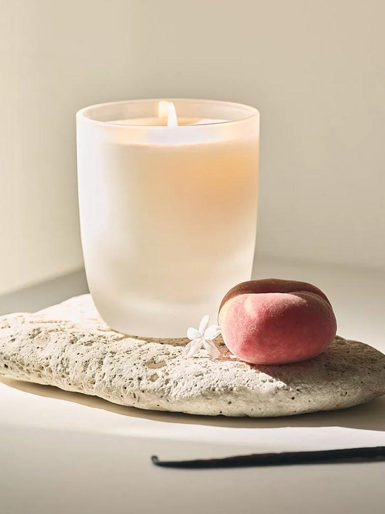 a candle sitting on a rock with a peach next to it