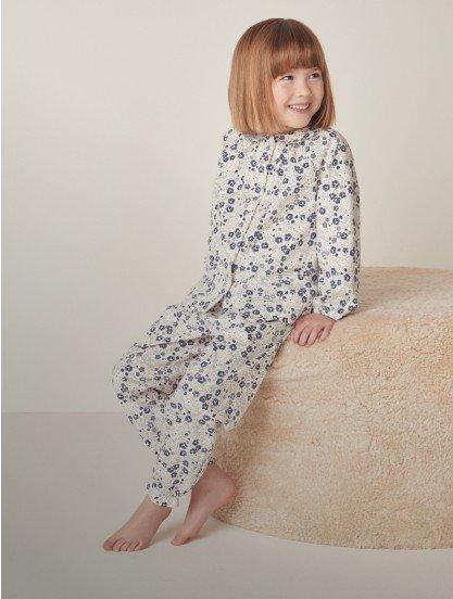 a little girl sitting on a pillow wearing a pajama set