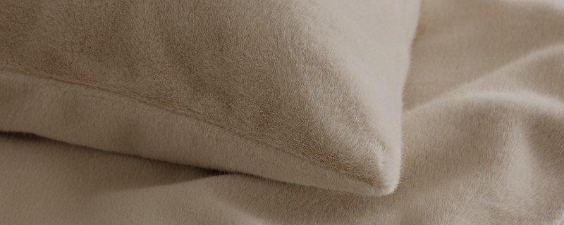 a close up of a bed with a pillow and a blanket