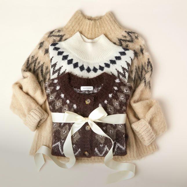 a sweater with a bow on it is sitting on top of another sweater