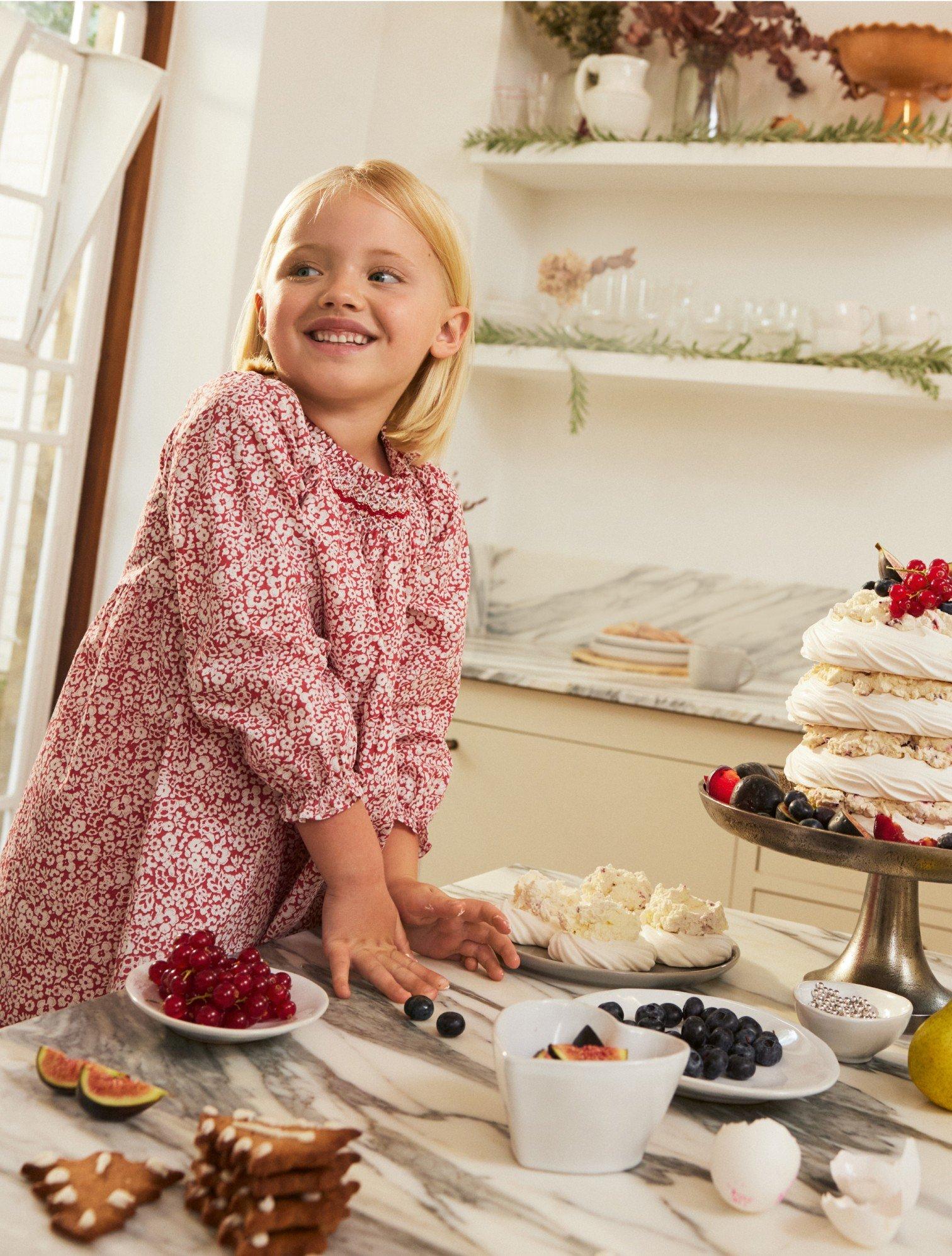 a little girl standing in front of a table with a cake on it