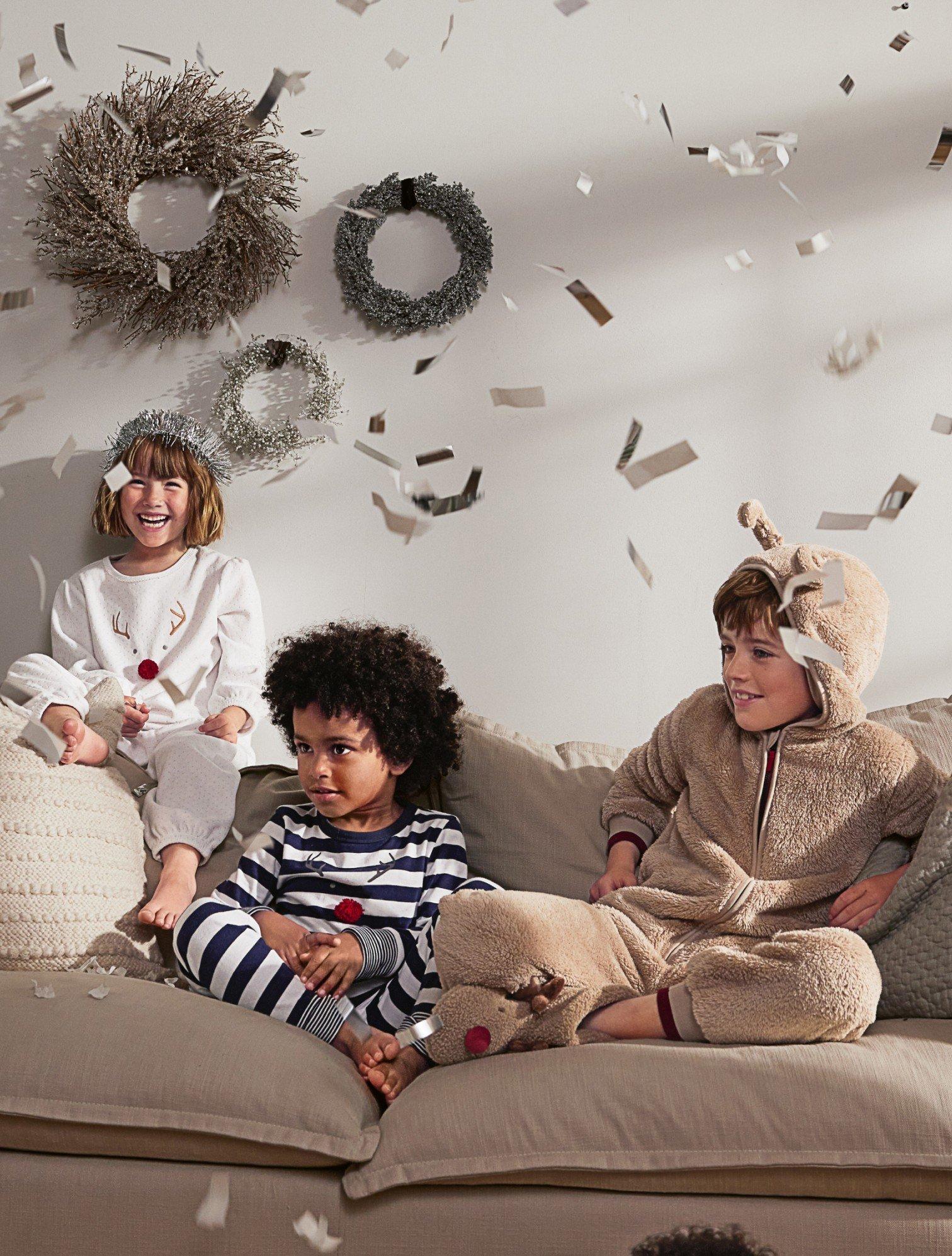 three children sitting on a couch with confetti falling from the ceiling