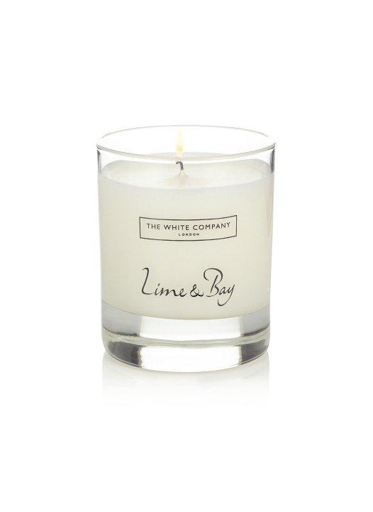 a white candle with a label that says lime and bay