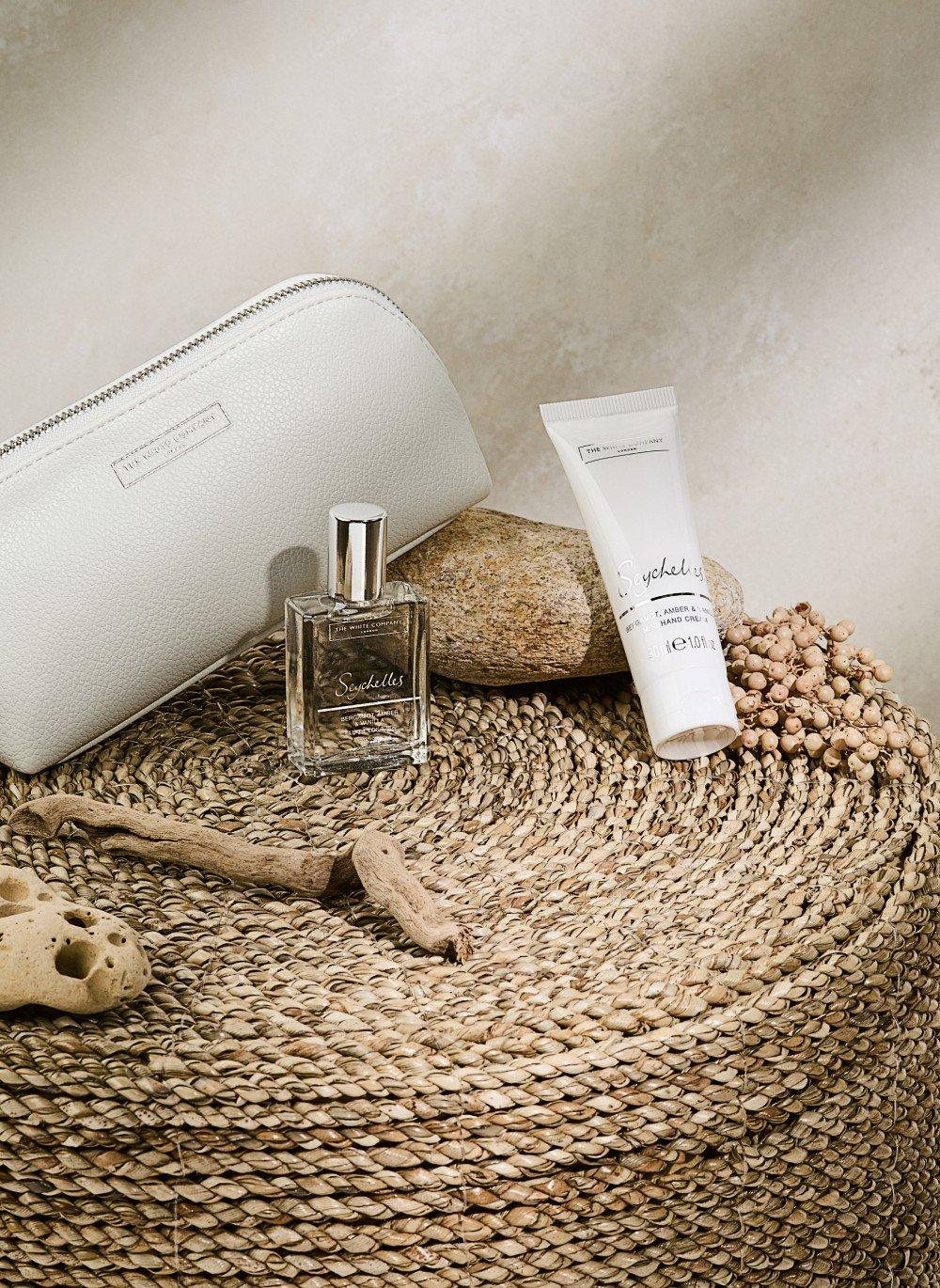 a white bottle of perfume sitting on top of a round wicker basket