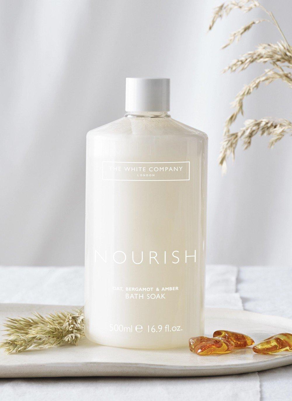 a bottle of nourish on a white plate with some flowers