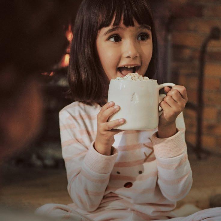 a little girl holding up hot chocolate