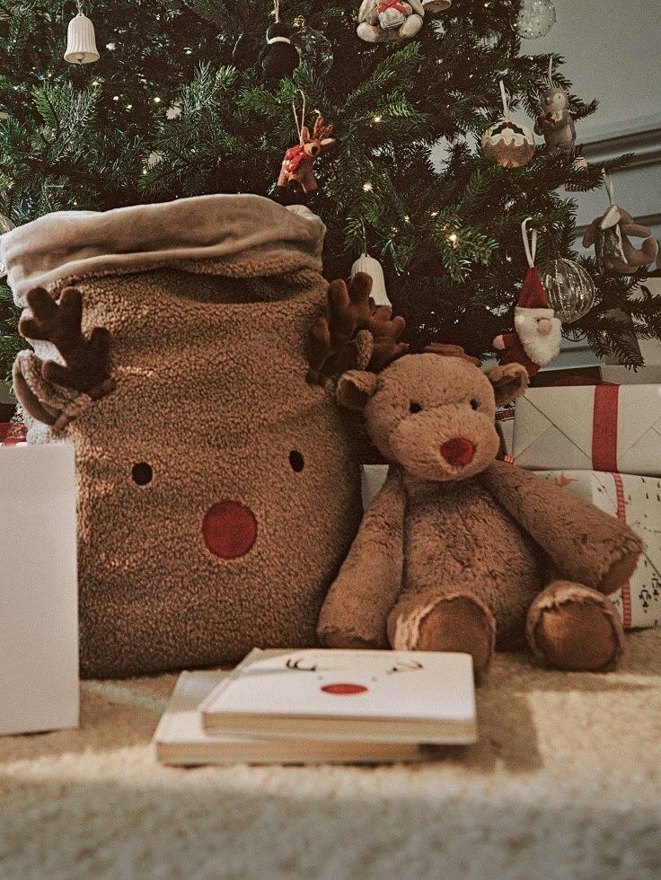 two babies laying on the floor next to a stuffed reindeer