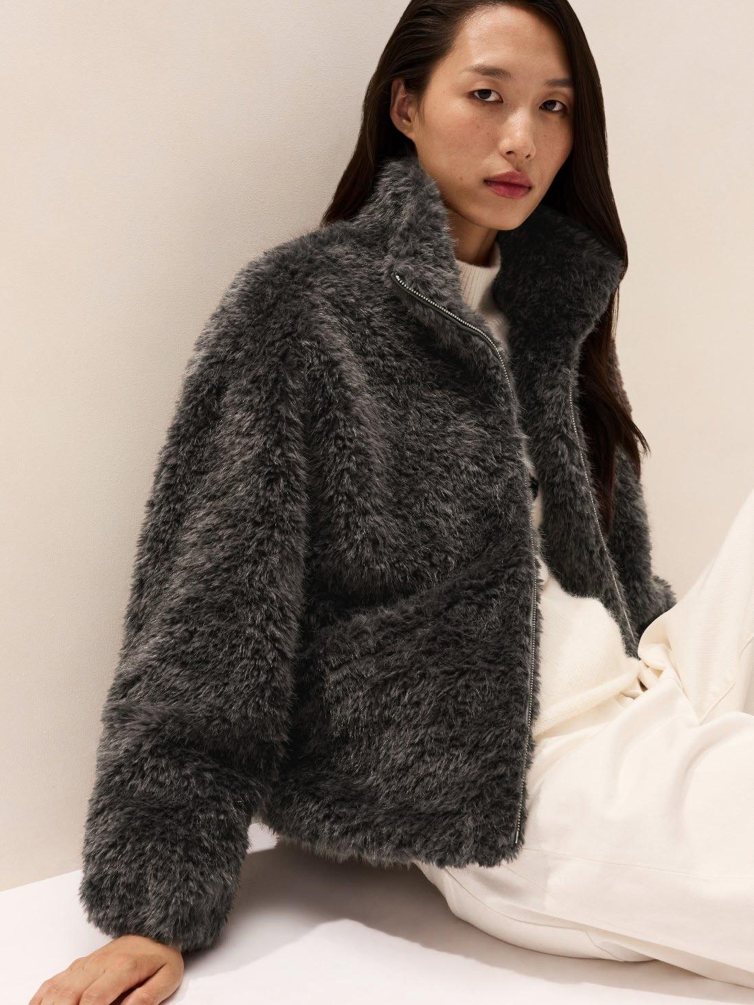 a woman in a furry jacket sitting on the floor