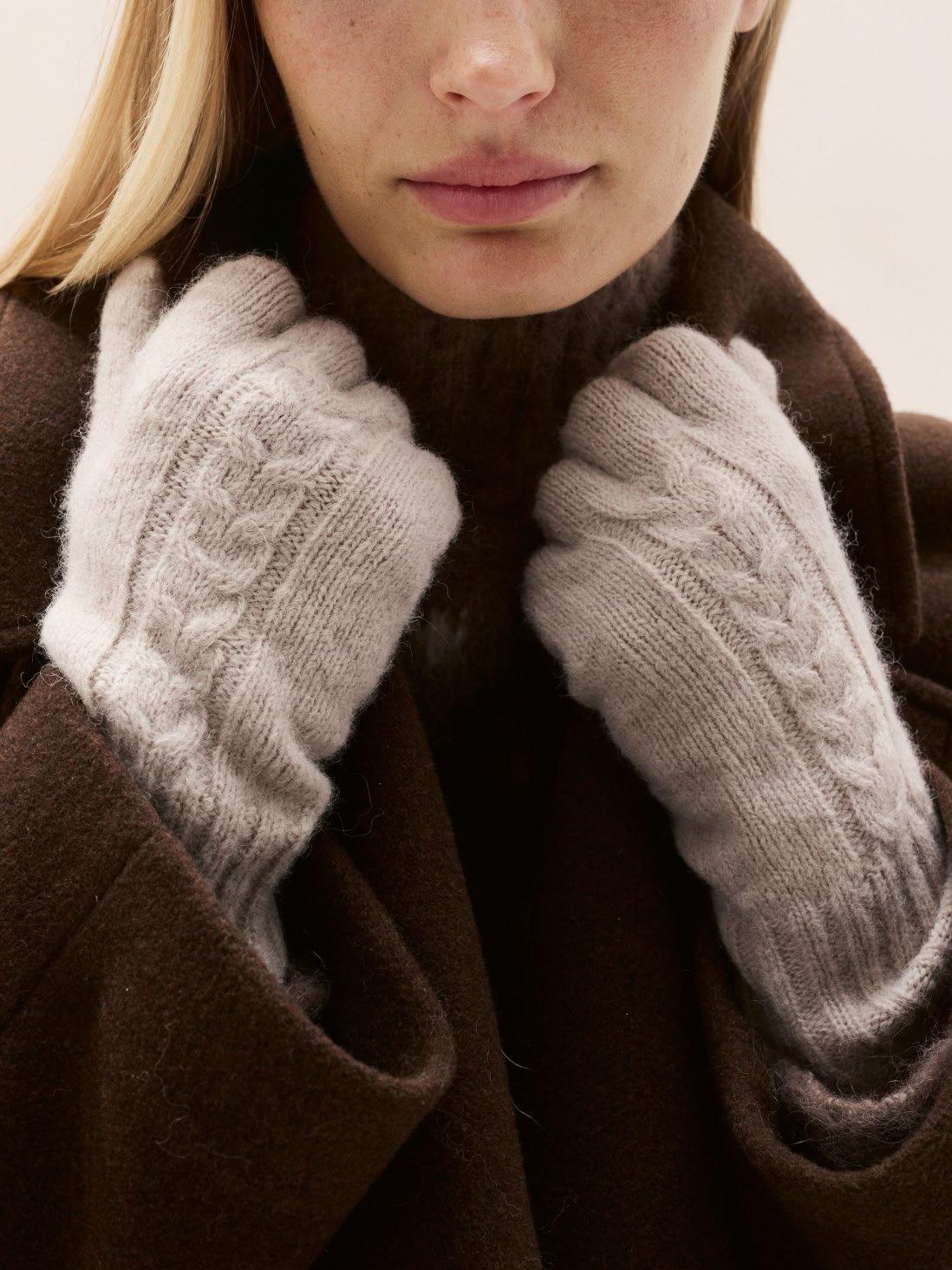 a woman with a coat and gloves holding her hands to her face