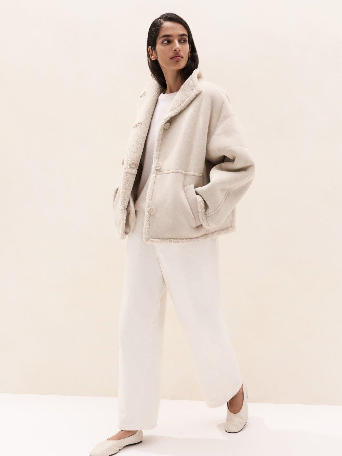 a woman in white pants and a jacket is standing