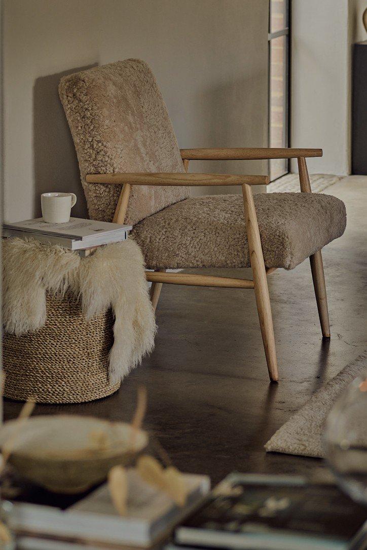 a living room with a chair and a mirror in front of a fireplace