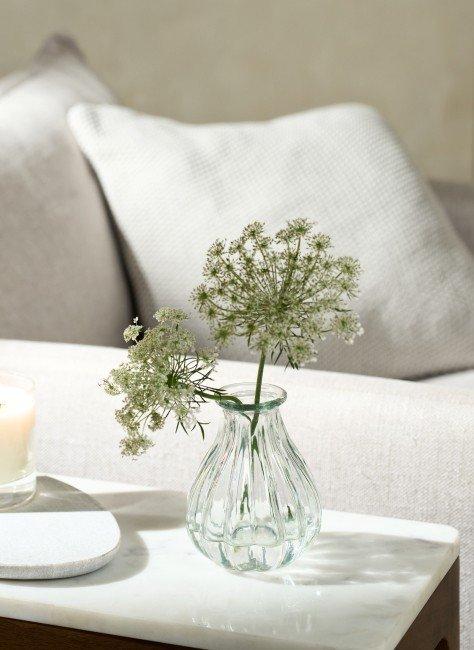 a small vase with flowers on a table next to a candle