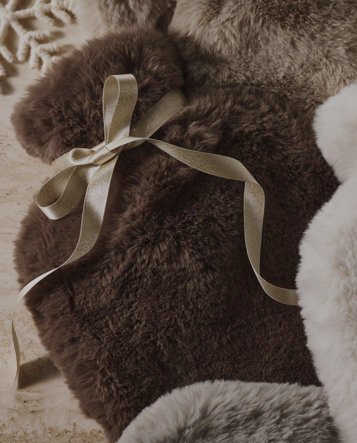 a hot water bottle wrapped in a white ribbon sits on a table