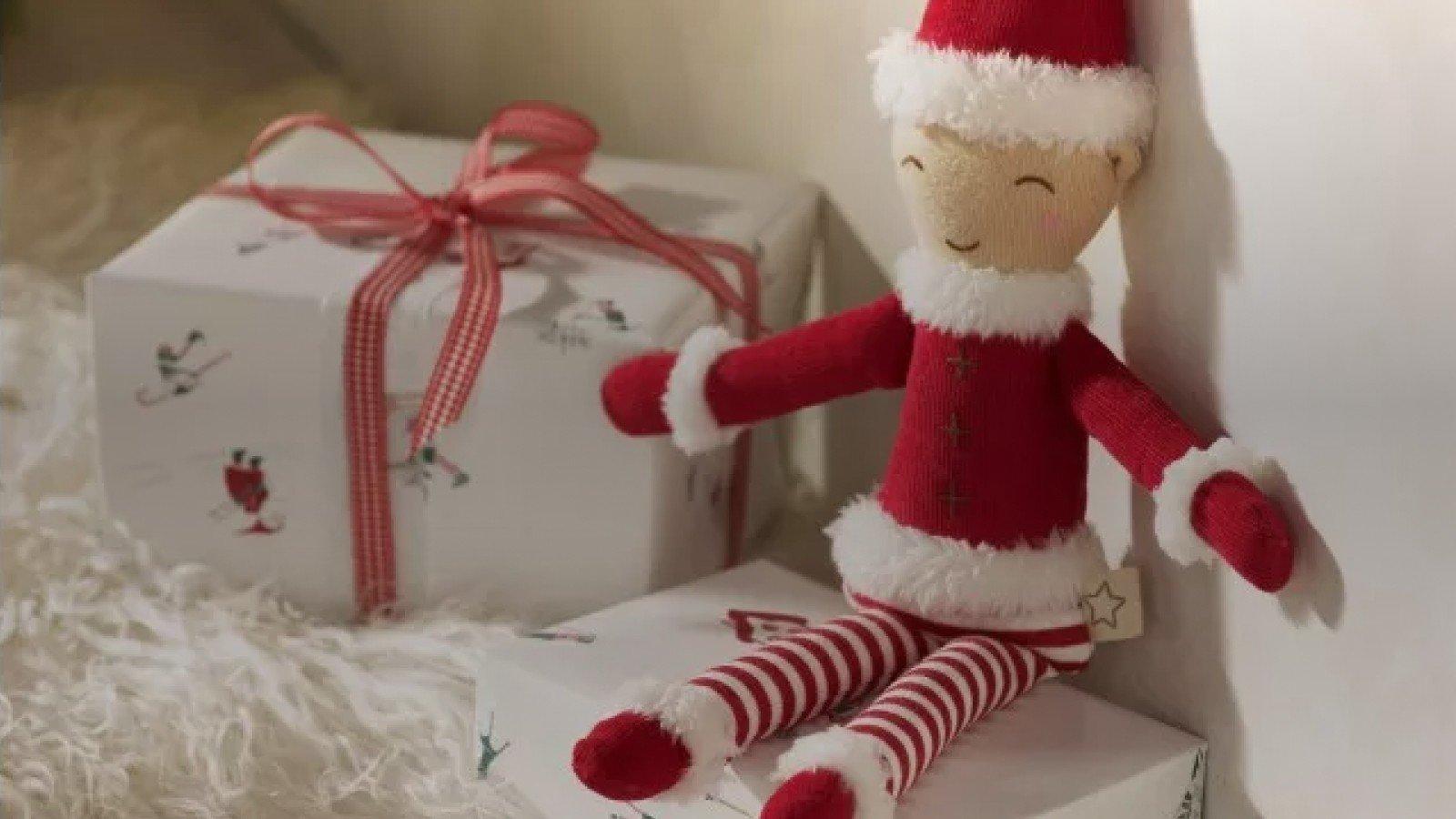 a small elf sitting on top of a box with a gift wrapped box next to it