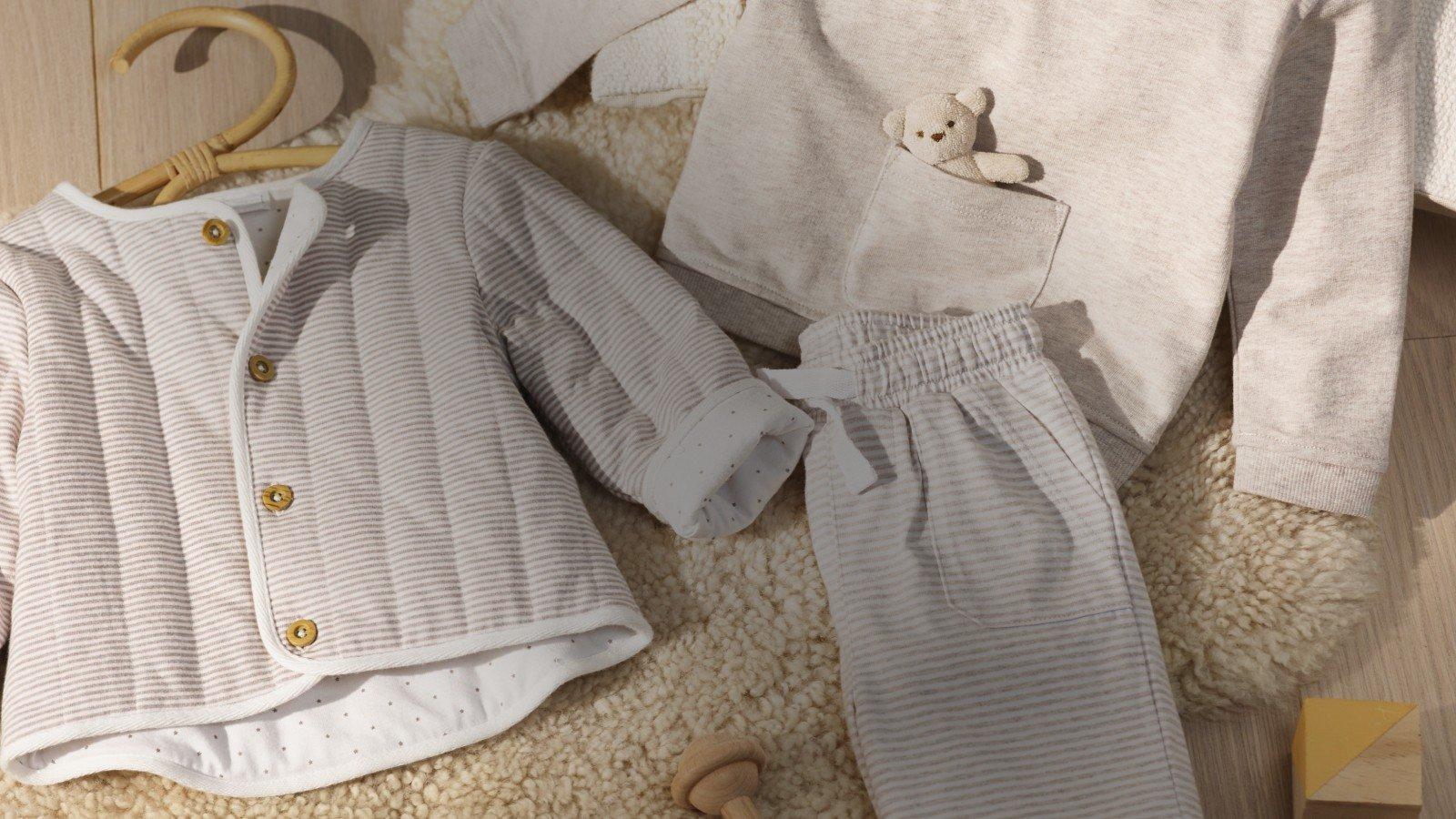 a baby's clothing is laid out on a wooden floor