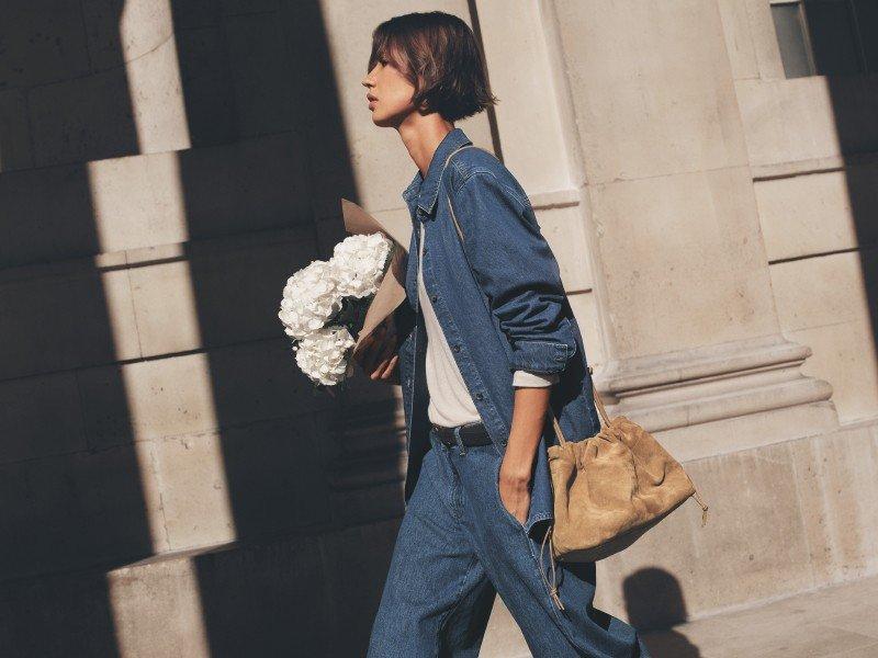 a woman standing in a hallway holding a coffee cup