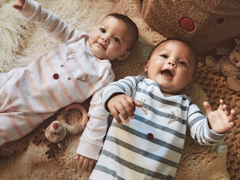 two babies laying on the floor next to a christmas tree