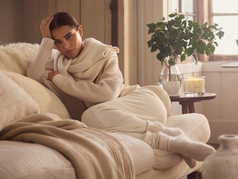 a woman in a white sweater sitting on a couch