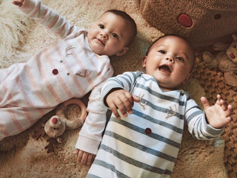 two babies laying on a bed with a toy in their hands