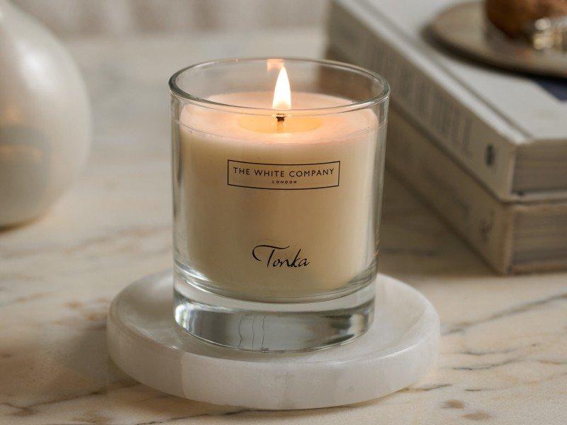 a candle sitting on a marble table next to a bowl of fruit
