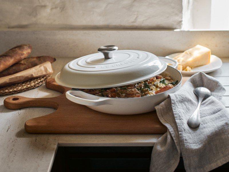 a white casserole dish sitting on a wooden cutting board