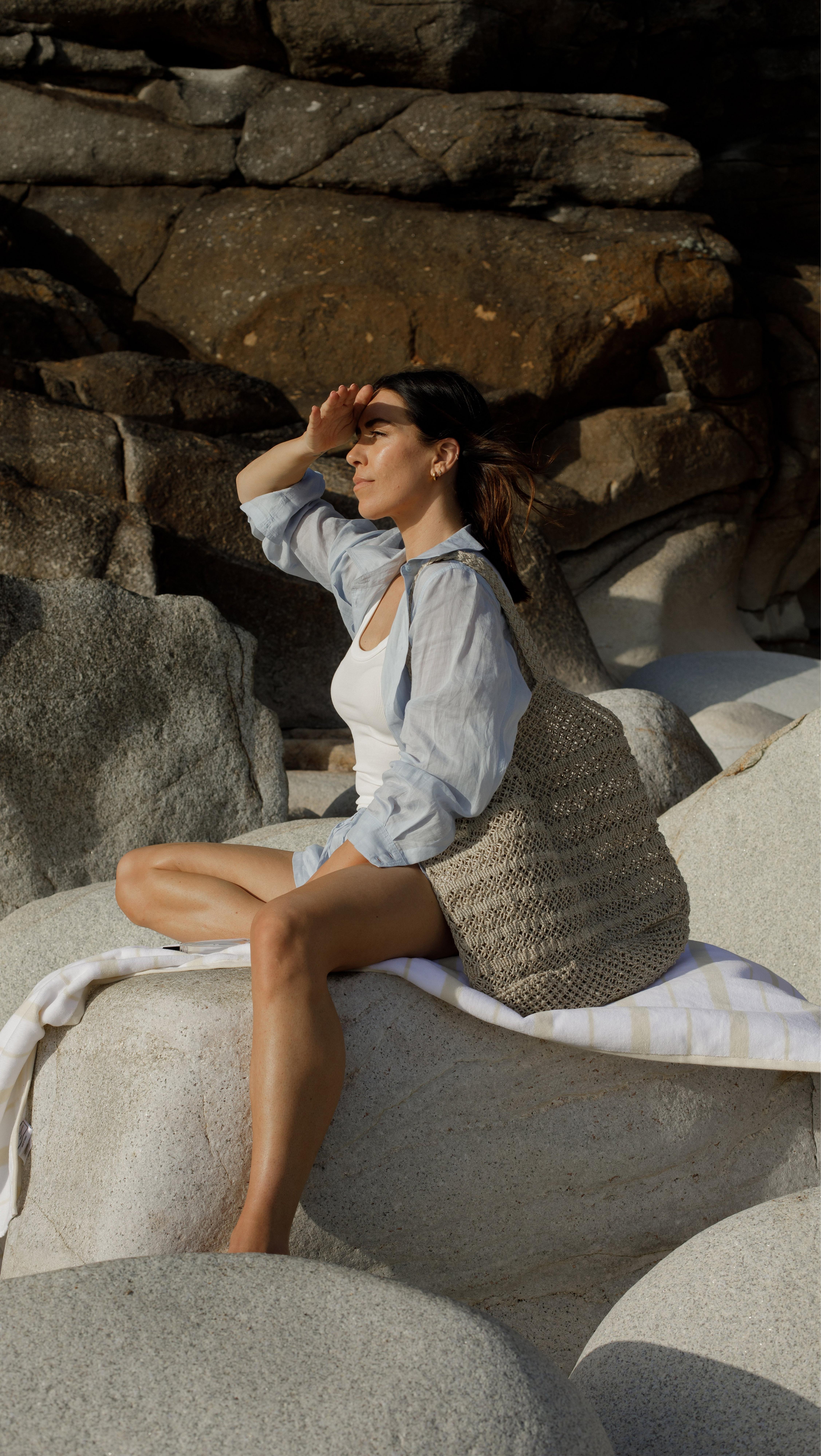 a woman sitting on a rock with a bag on her lap