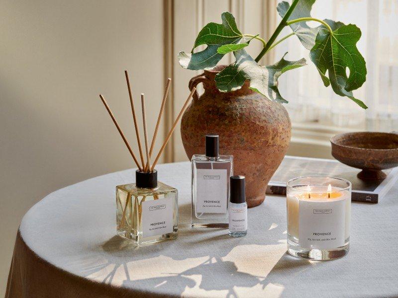 a table with a vase, candle, and perfume on it