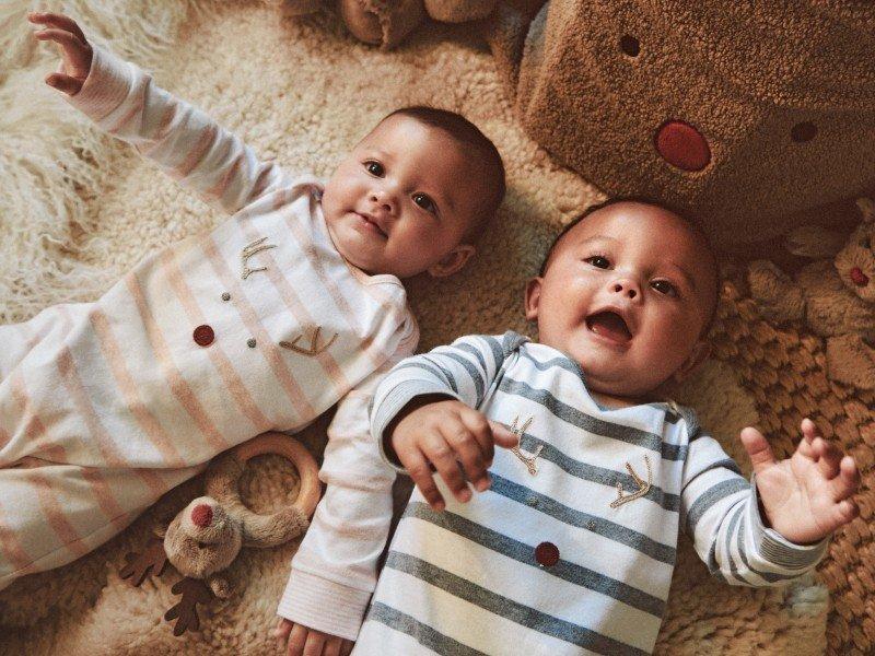 a baby sitting on a bed with a stuffed animal
