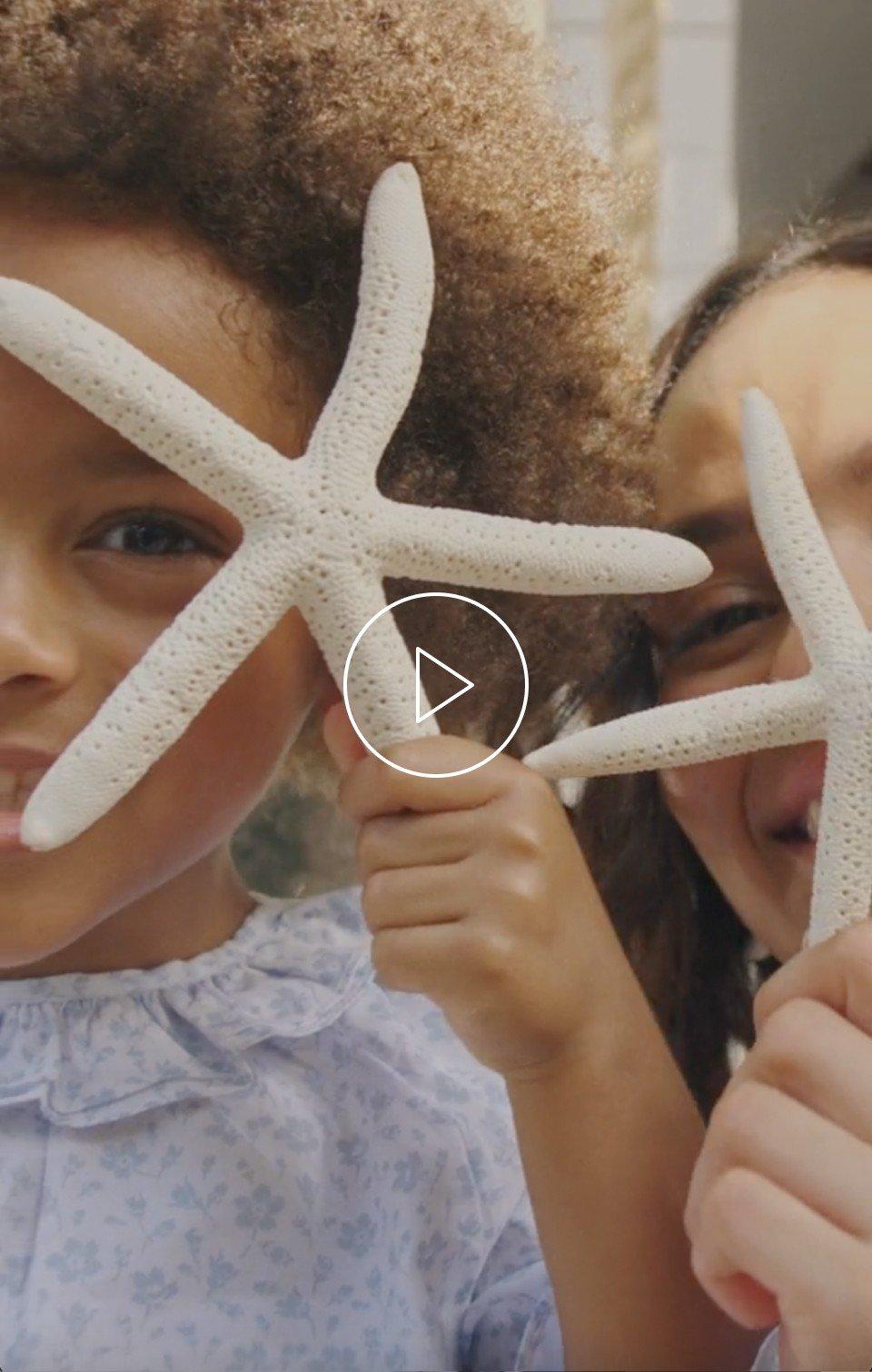 two girls holding up starfish in front of each other