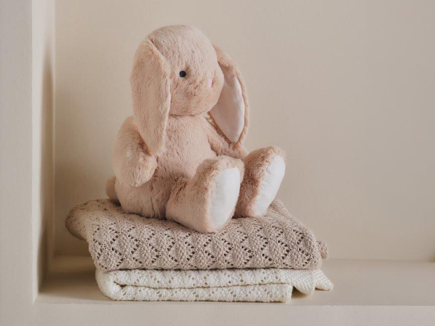 a stuffed bunny sitting on top of a stack of towels