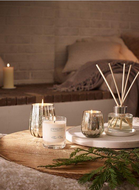 a table with candles and a plant on it next to a couch