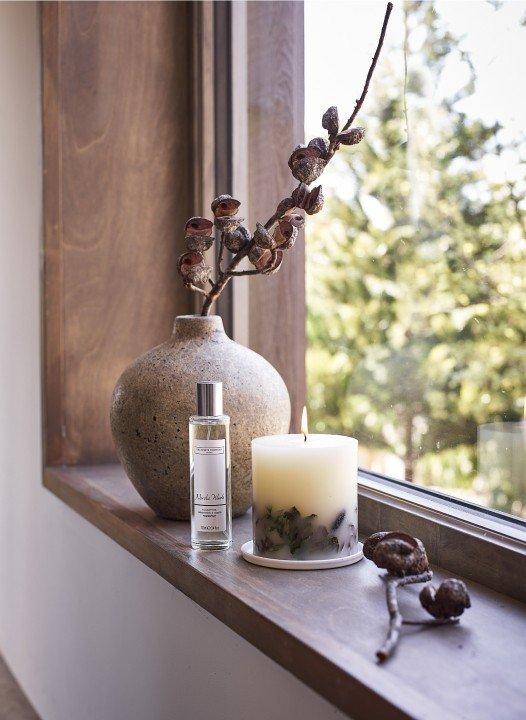 a vase with flowers and candle on window sill