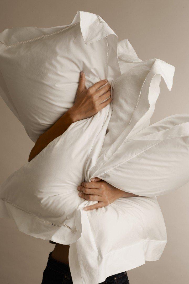 a woman is holding a pillow over her head and another over her body