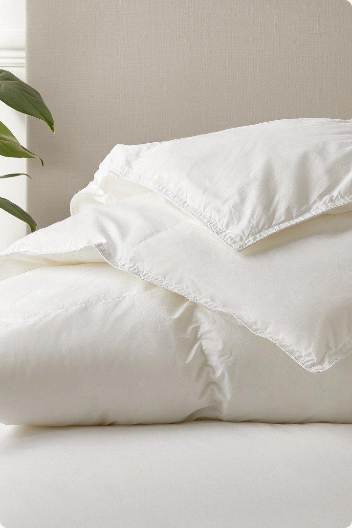 a bed with a white comforter and pillows on top of it