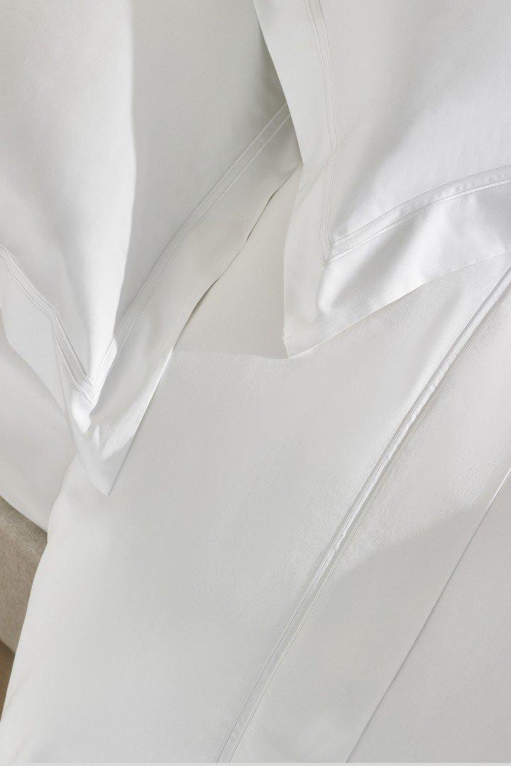 a white bed with a white comforter and pillows on it