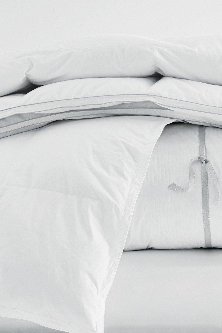 a bed with a white comforter and pillows on top of it