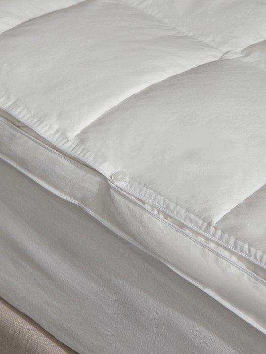 a close up of a pillow on a bed with a white cover