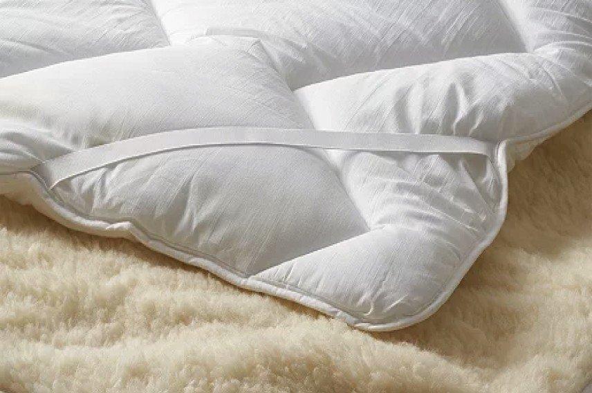 a bed with a pile of white pillows and blankets on top of it