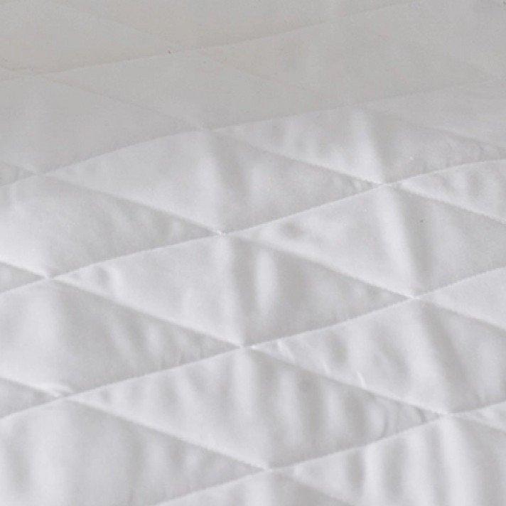 a pile of pillows on a bed with a white sheet