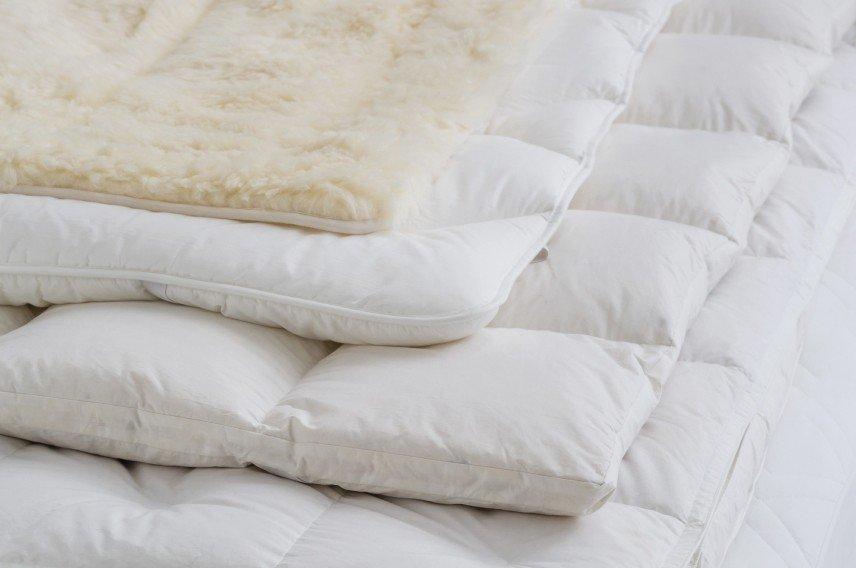 a bed with a pile of white pillows and blankets on top of it