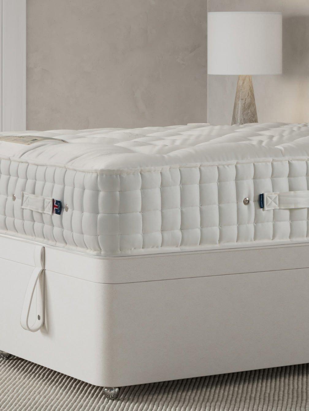 a white bed with a white mattress and a white headboard