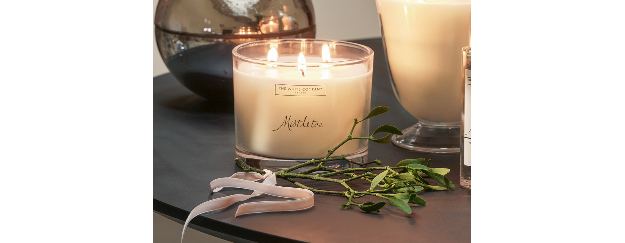 a candle and a plant sit on a table next to a glass