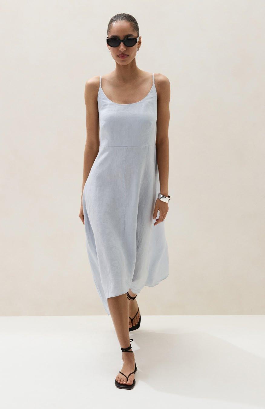 a woman in a white dress and sandals walking