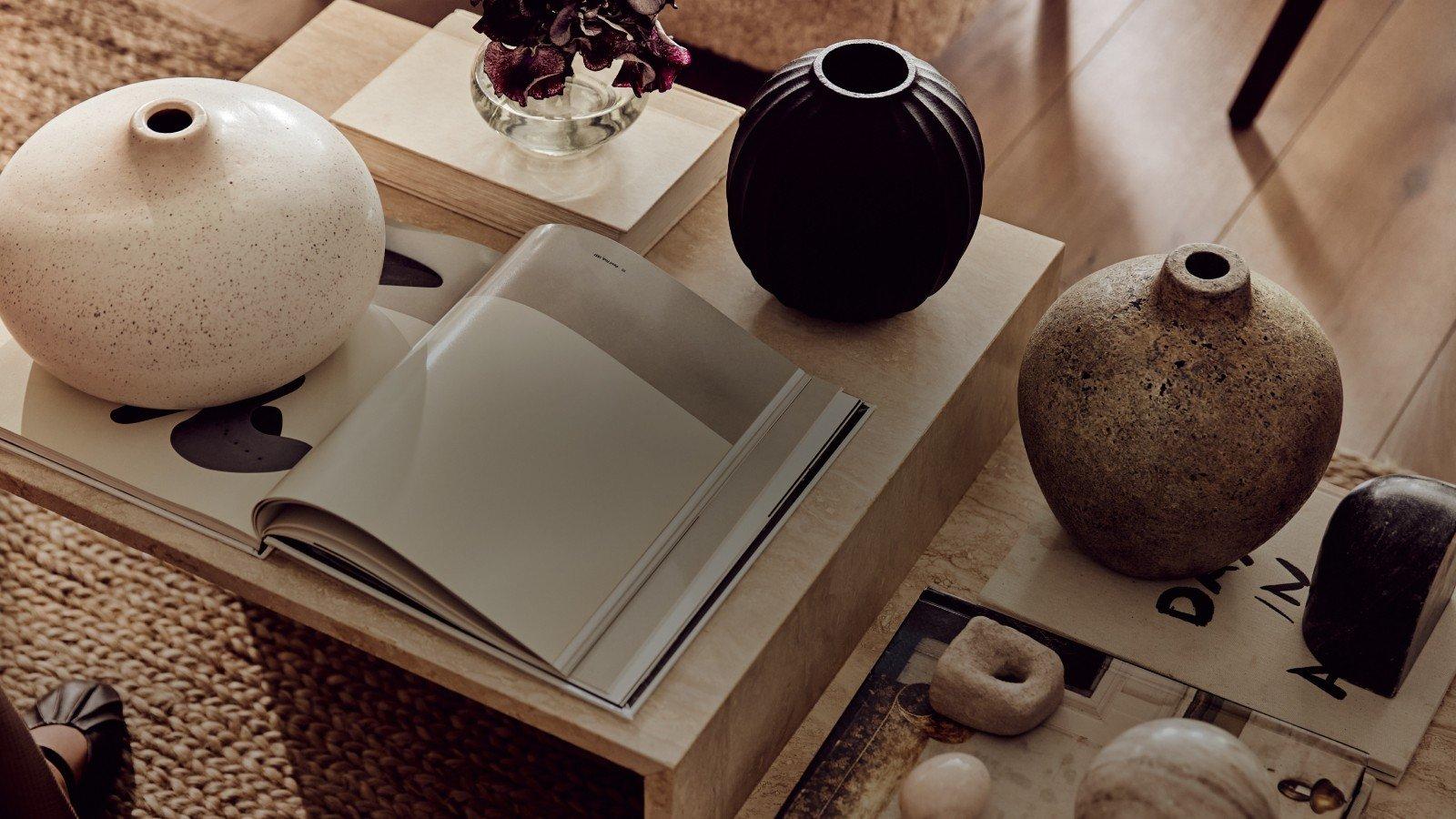 a table with vases and a book on it in a living room