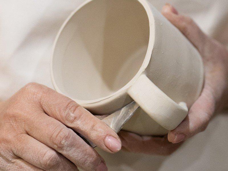 a person holding a cup with a knife in it