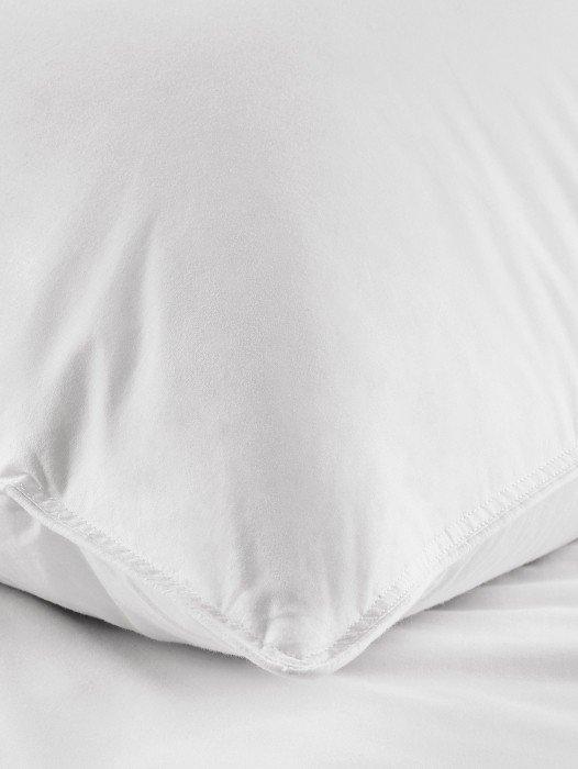 a close up of a pillow on a bed with a white cover